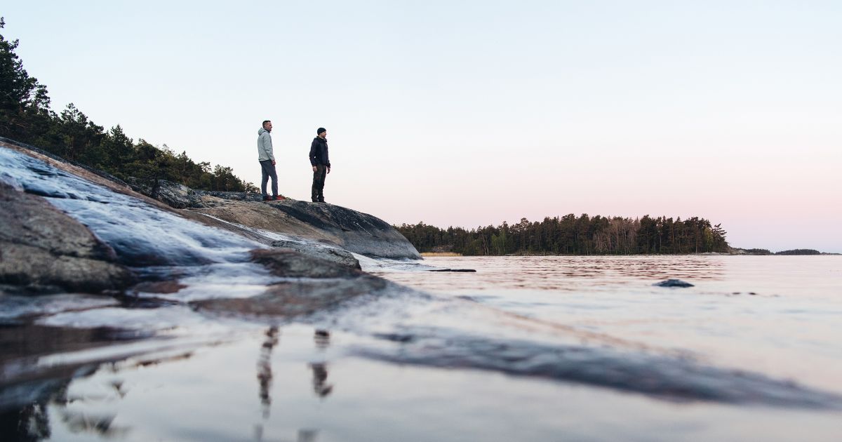 kaksi henkilöä seisoo rannalla